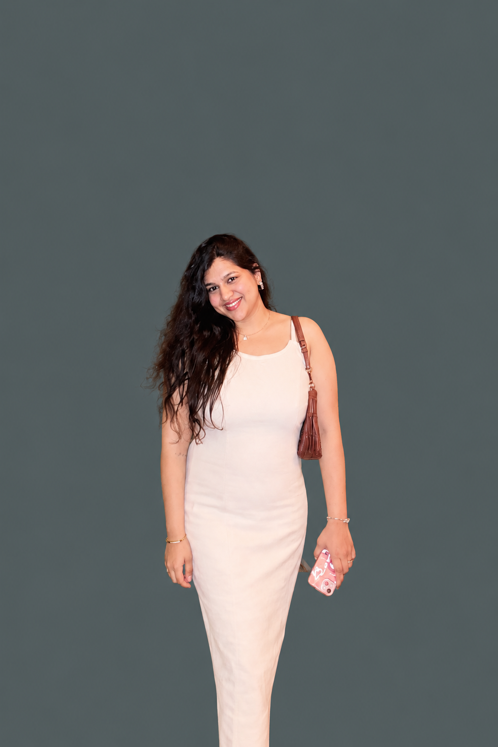 Portrait of Aarushi Aggarwal in a cream slip dress against a slate background.